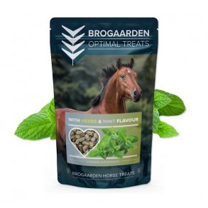 En pose Brogaarden Optimal Treats med urter og pebermynte. Bagved posen er et billede af urter